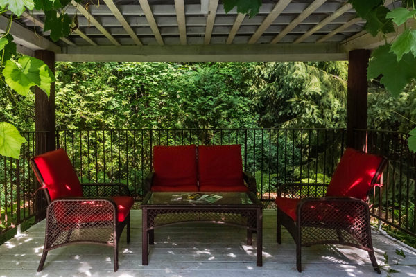 Outdoor patio with red cushions under a pergola.